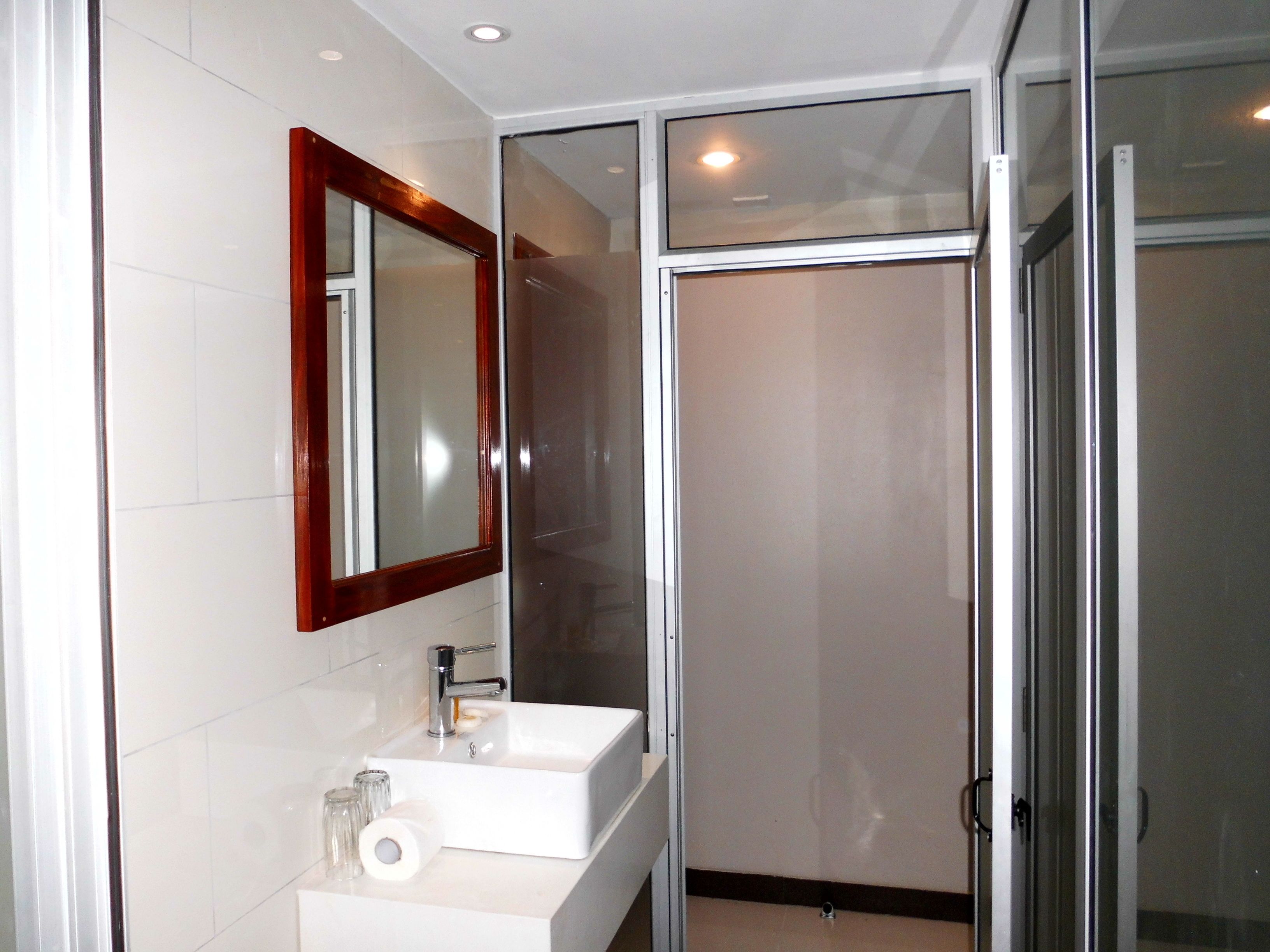 A modern bathroom with a white sink, a mirror with a wooden frame, and a glass shower enclosure.