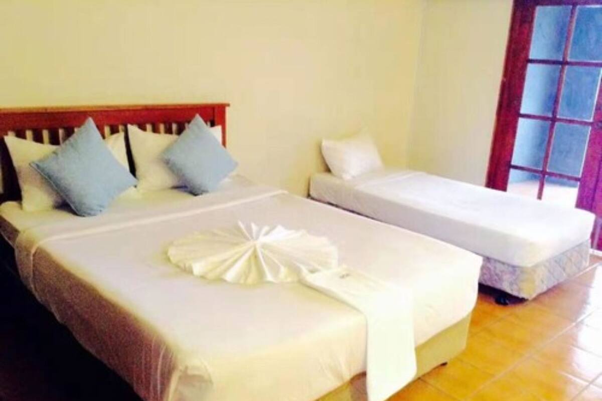 A hotel room with two beds, one larger and one smaller, both with white linens and pillows.
