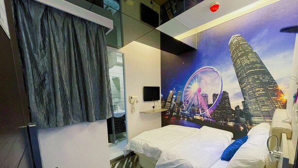 A hotel room with a bed, a mirror, a bathroom, and a cityscape mural on the wall. - Move Inn (Hong Kong)