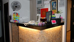 A hotel reception desk with a telephone, a computer, and various items on the counter. - Move Inn (Hong Kong)