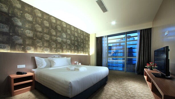 A hotel room with a large bed, a TV, a nightstand, and a window with a view of buildings. - Izumi Hotel Bukit Bintang (Kuala Lumpur)