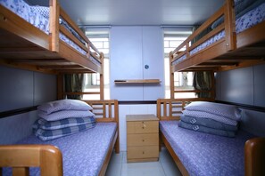 A bunk bed room with two beds, a small dresser, and a window. - H.K Commercial Inn (Kowloon)