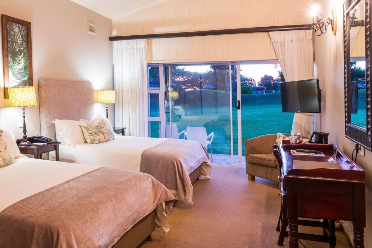 Una habitación de hotel con dos camas, un escritorio, una silla y un televisor.