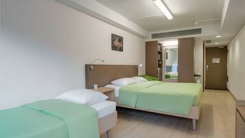 A hotel room with two beds, a wooden headboard, a small bedside table, and a mirror.