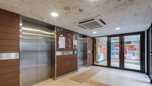Ein moderner Aufzugsbereich mit Edelstahl- und Holzverkleidungen, einem gut lesbaren Grundriss und einer Decke mit verschiedenen Schriftzügen.