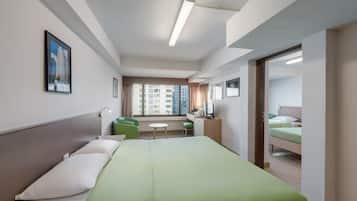 A hotel room with a bed, a desk, a chair, a TV, and a window with a view of buildings.