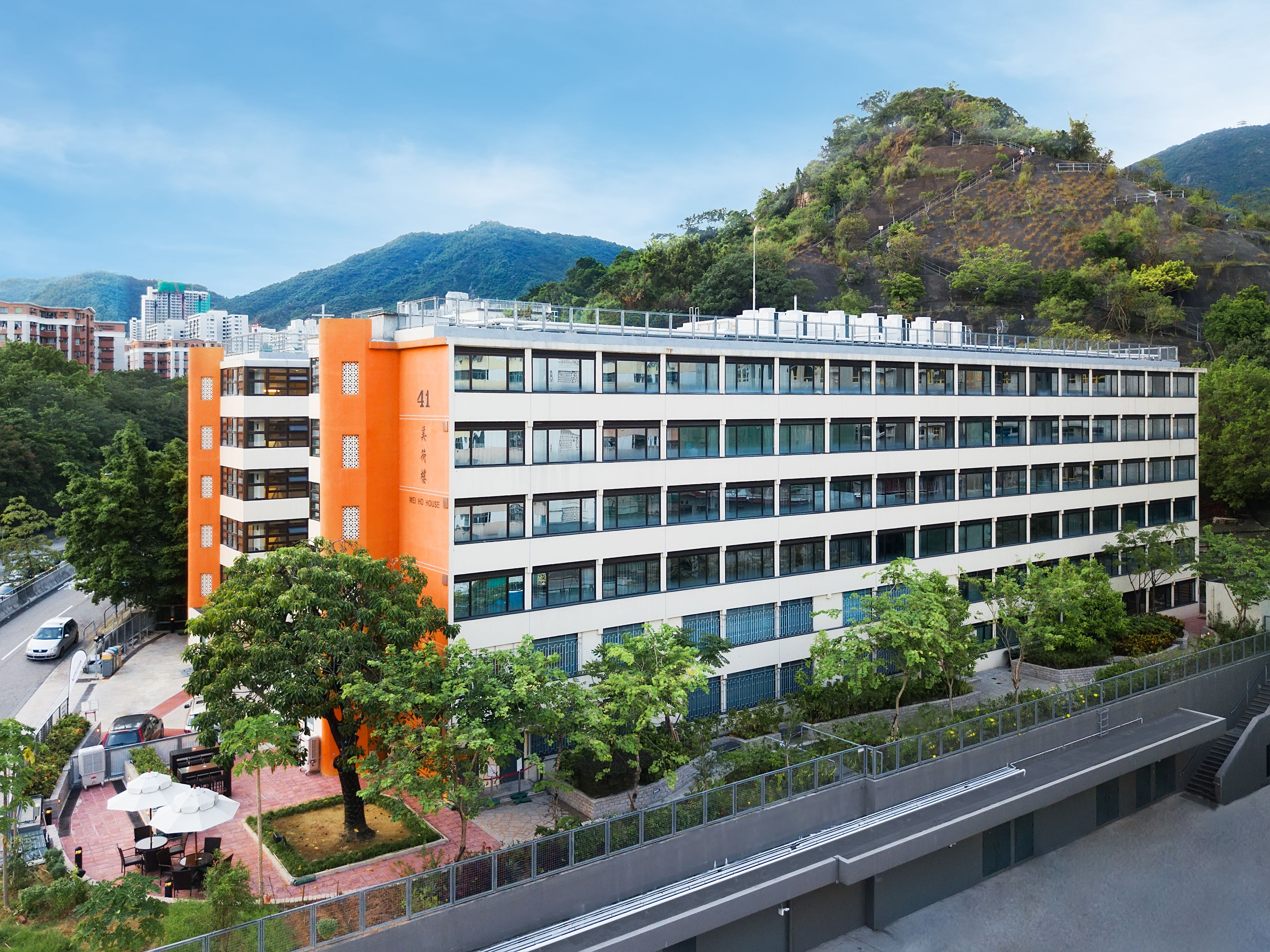 A multi-story hotel with a modern design, featuring a prominent orange tower and multiple balconies.