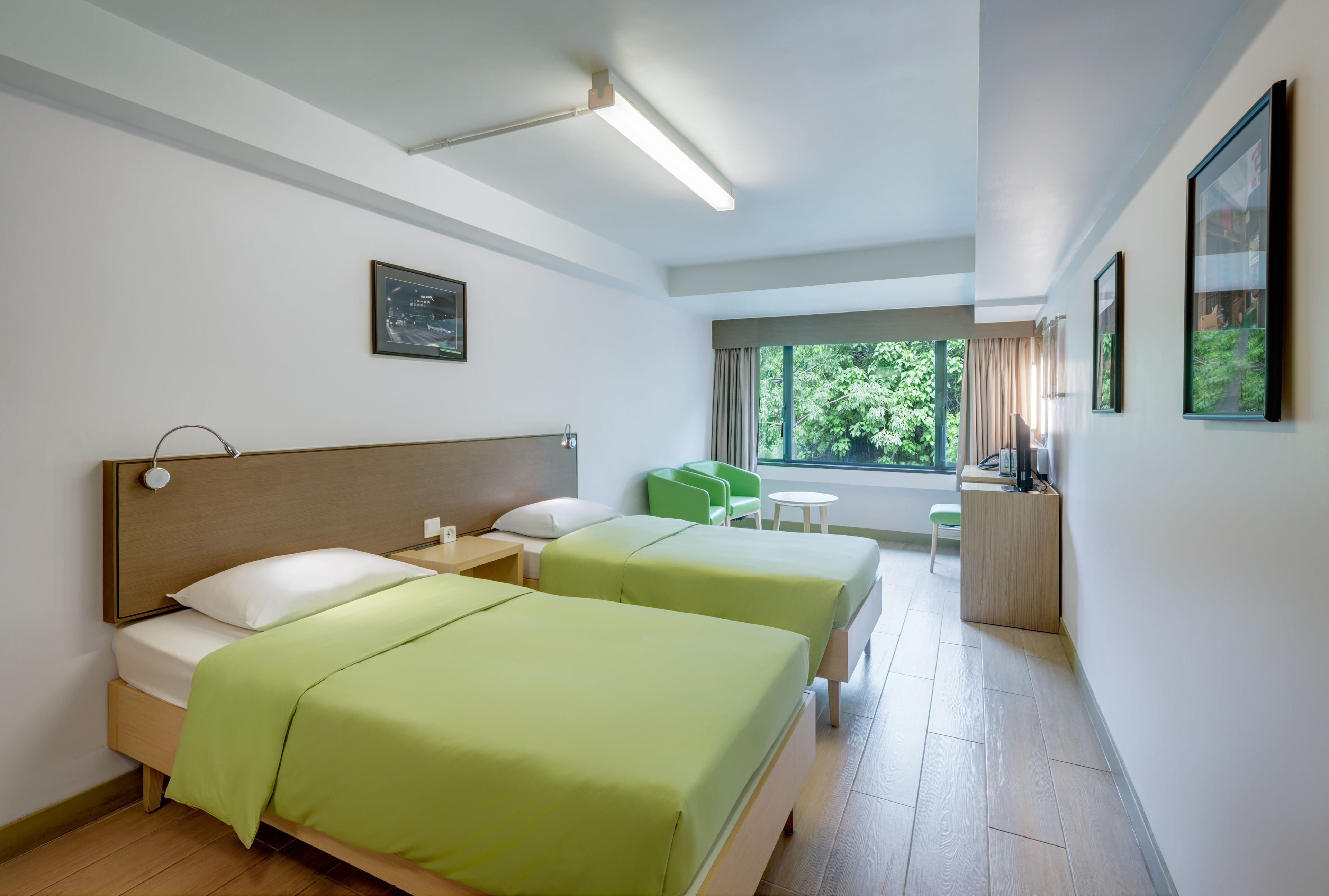Une chambre d’hôtel avec deux lits, un bureau et une vue sur la verdure.