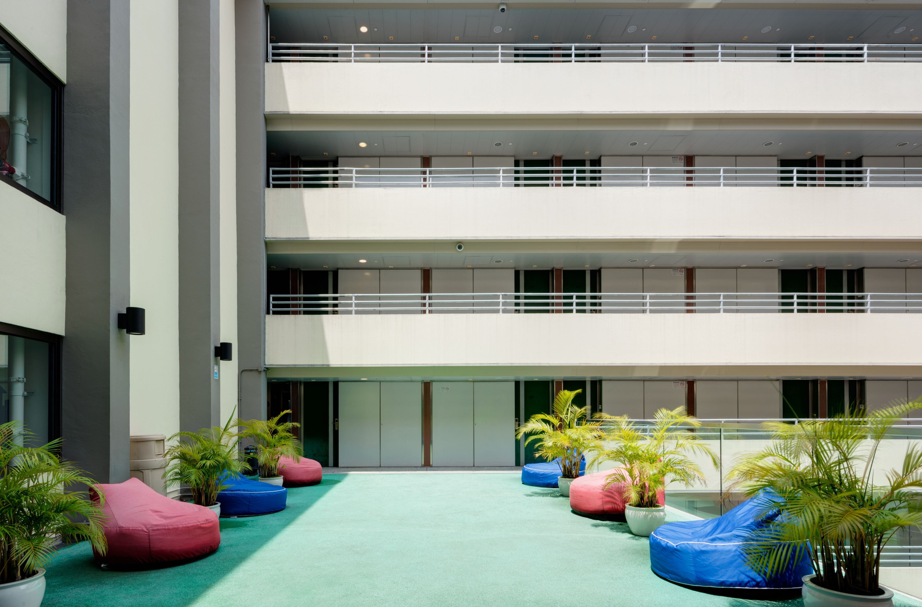 A multi-level atrium with a green carpeted floor, multiple seating areas, and potted plants.