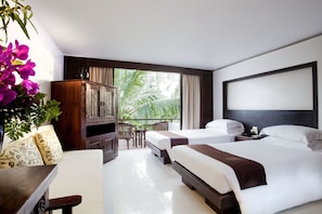 A hotel room with two beds, a wooden cabinet, a desk, and a view of palm trees.