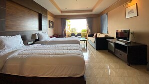 A hotel room with two beds, a TV, a desk, and a balcony with outdoor seating. - Baan Kongdee Sunset Resort (Karon)