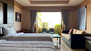 A hotel room with a large bed, a sofa, a small table, and a balcony with chairs. - Baan Kongdee Sunset Resort (Karon)