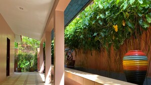 A corridor with a tiled floor, a bench, and a wall covered in greenery. - Baan Kongdee Sunset Resort (Karon)