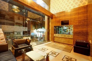 A lobby with a glass wall, leather seating, a reception desk, and patterned walls. - Arafa Inn (Bengaluru)