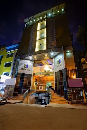 A hotel with a modern design, featuring a prominent entrance with glass doors and a staircase leading up to the lobby. - Arafa Inn (Bengaluru)