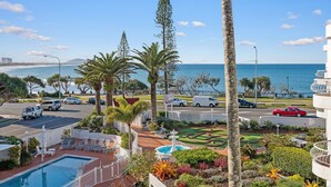 A resort with a pool, landscaped garden, and a view of the ocean. - Alexandria Apartments (Alexandra Headland)