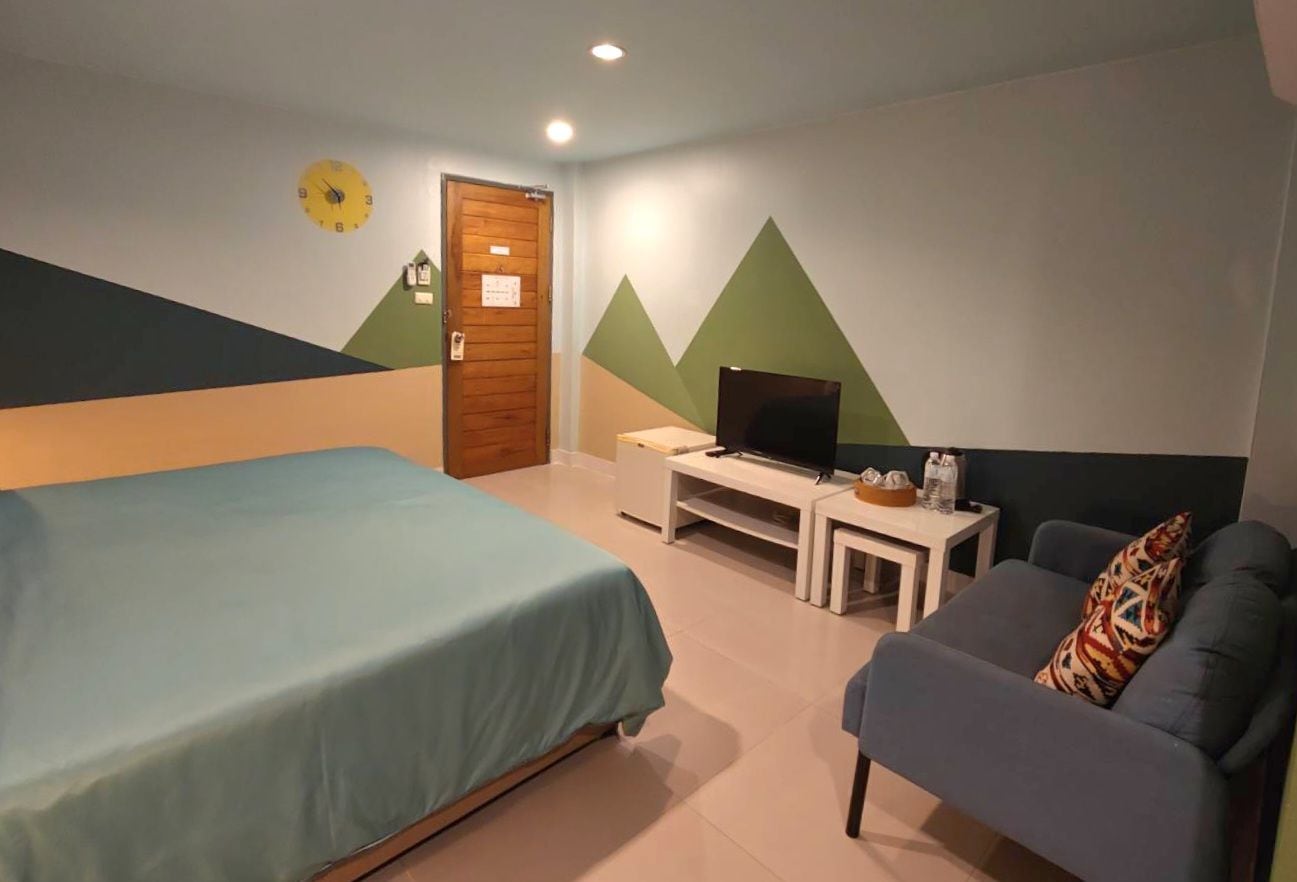 Quarto com cama, televisão, sofá e porta.