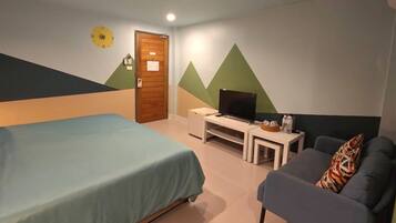 Quarto com cama, televisão, sofá e porta.
