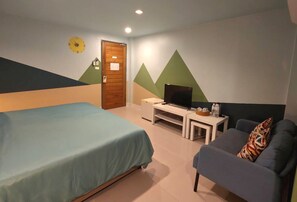A bedroom with a bed, a TV, a sofa, and a door. - Limburi Hometel (Patong)