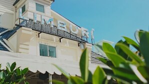 A building with the name "LIMBURI" on the facade, featuring a balcony with railings and a tiled roof. - Limburi Hometel (Patong)