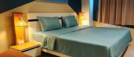 A hotel room with a bed, nightstands, a lamp, a painting, and a view of the outside.