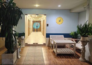A hotel lobby with a reception desk, seating area, and a clock on the wall. - Limburi Hometel (Patong)