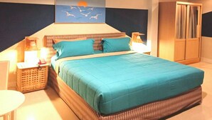 A bedroom with a large bed, a nightstand, a lamp, a wardrobe, and a painting of birds. - Limburi Hometel (Patong)