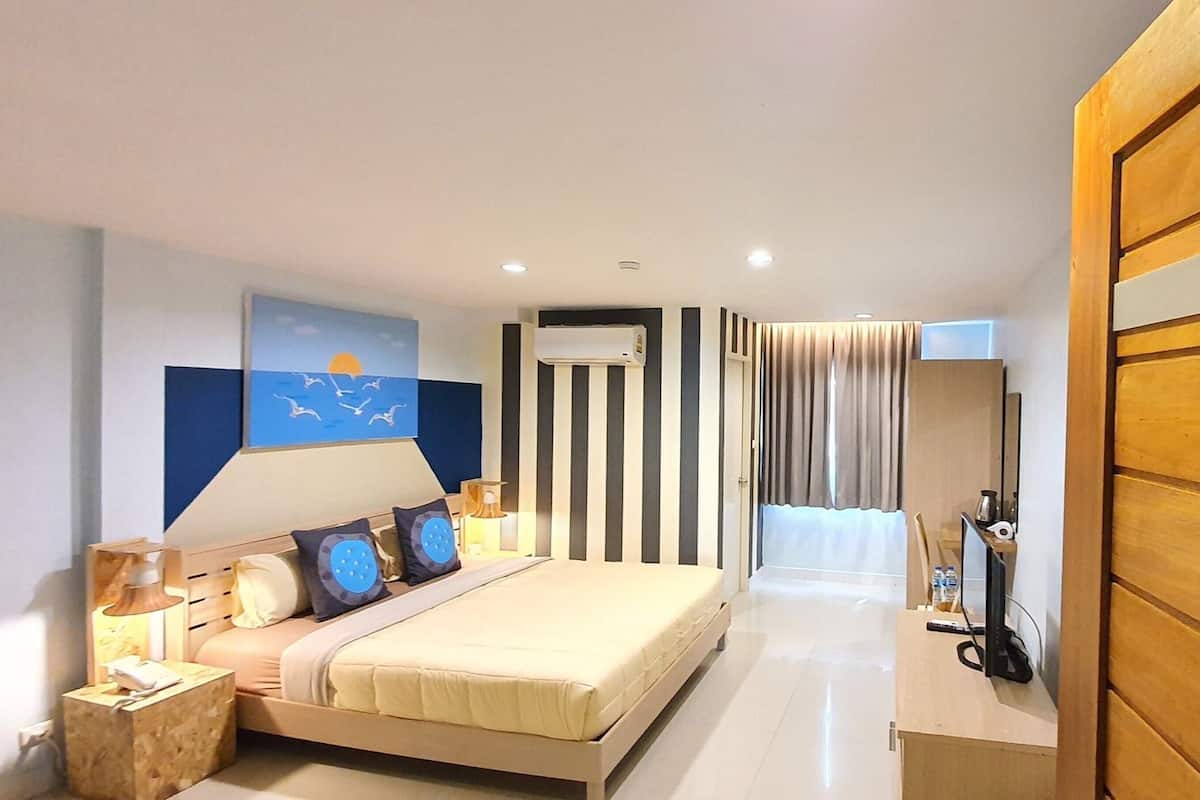 A modern hotel room with a bed, bedside table, lamp, and a view of the hallway.