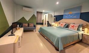 A bedroom with a bed, a desk, and a chair. There is a painting on the wall and a window with curtains.