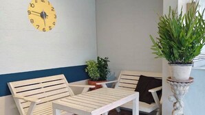 A seating area with two wooden benches, a small table, and a potted plant. - Limburi Hometel (Patong)