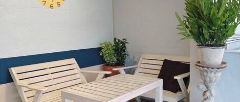 A seating area with two wooden benches, a small table, and a potted plant.