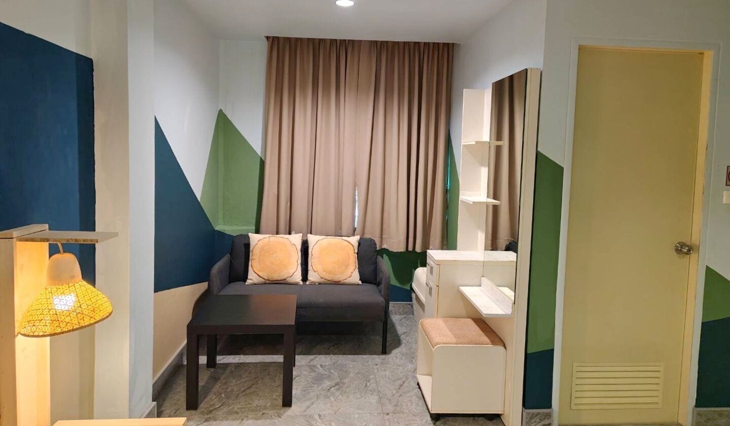 Een kamer met een bank, een tafeltje, een lamp en een deur.