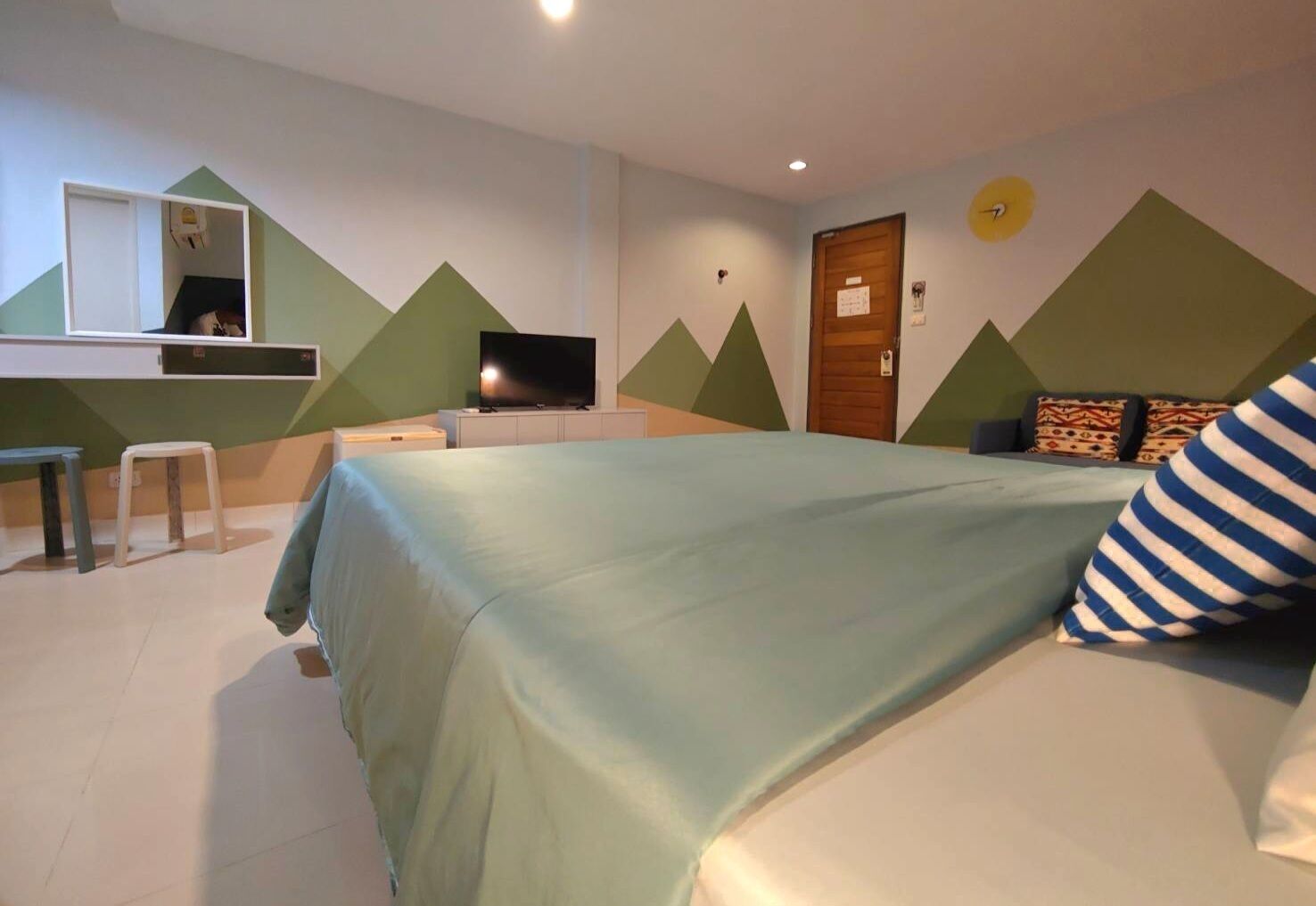 Un dormitorio con cama, escritorio, televisor y puerta.
