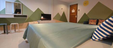Un dormitorio con cama, escritorio, televisor y puerta.