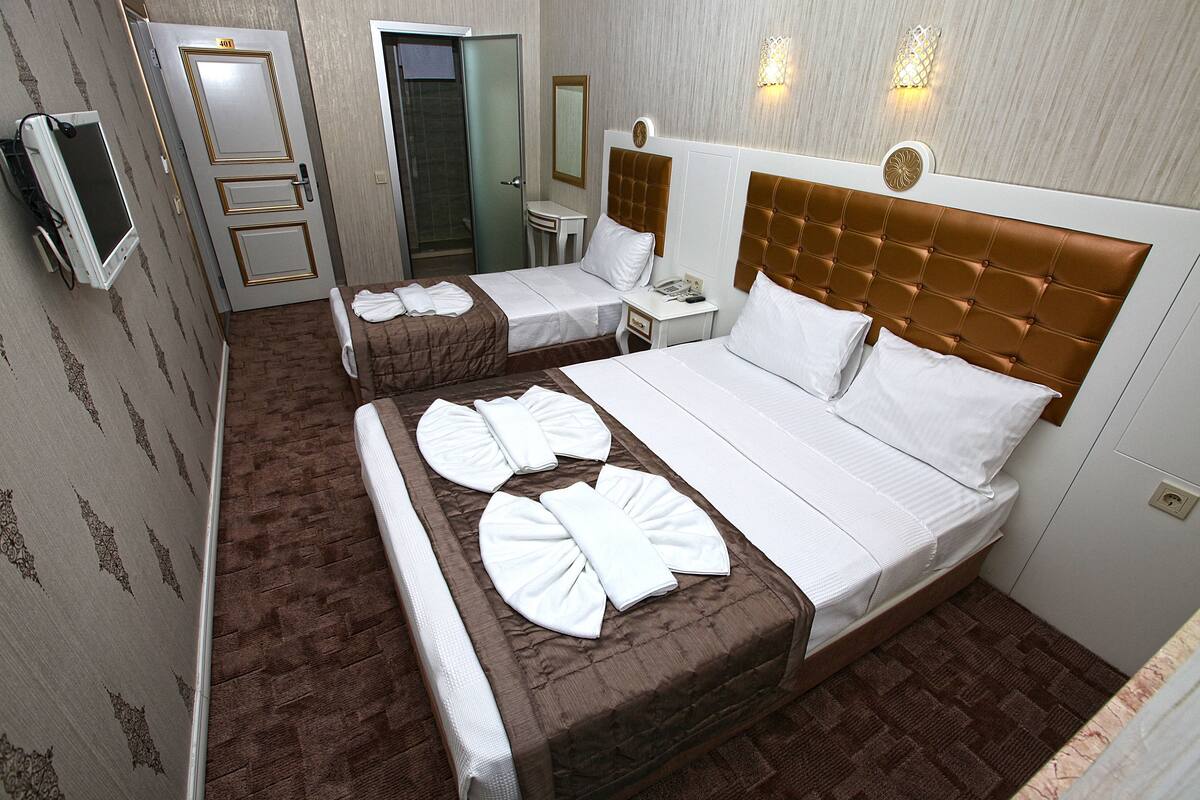 A hotel room with two beds, a desk, a mirror, and a TV.