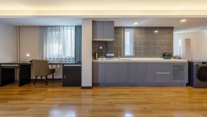 Una cocina moderna con lavavajillas integrado, cafetera y un amplio ventanal con cortinas.