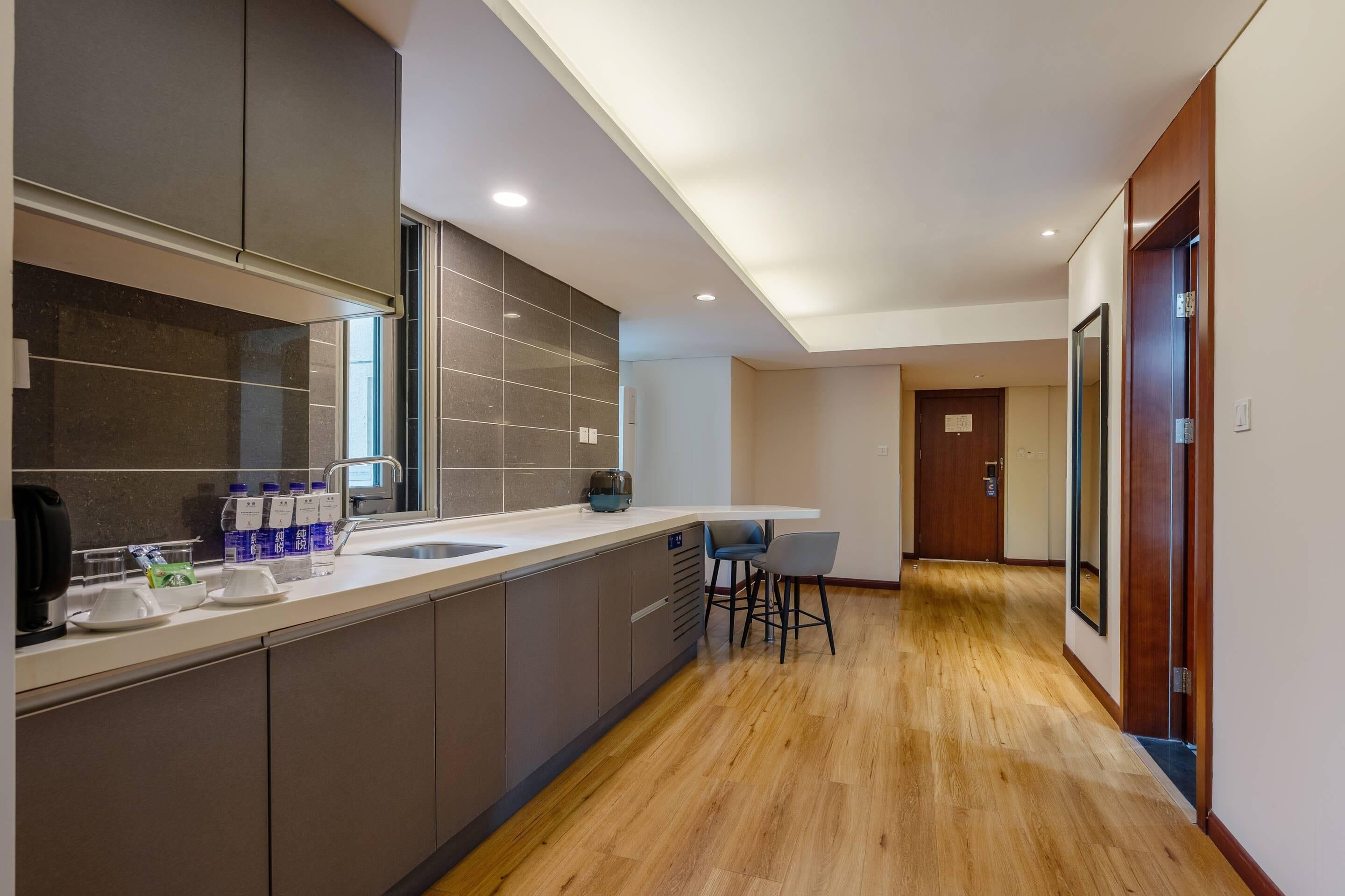 A modern kitchen with a large island, a built-in oven, and a refrigerator. There is a dining area with a table and chairs.