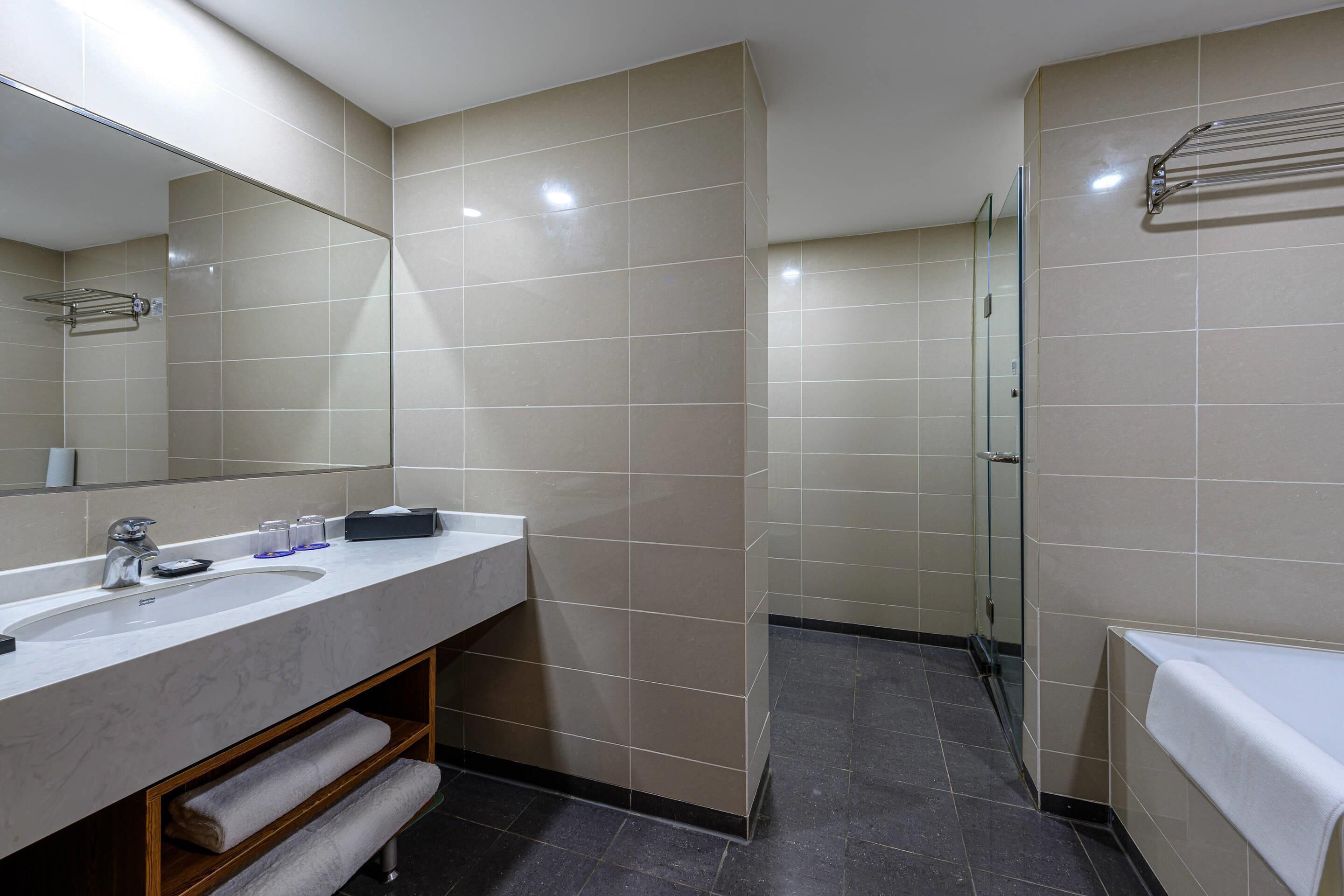 A modern bathroom with a marble sink, a glass shower enclosure, and a towel rack.
