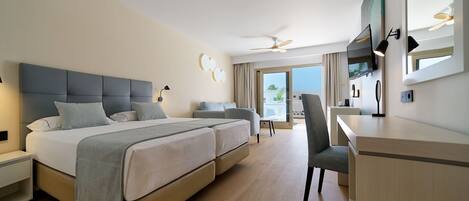 A hotel room with a large bed, a desk, a chair, a ceiling fan, and a large window.