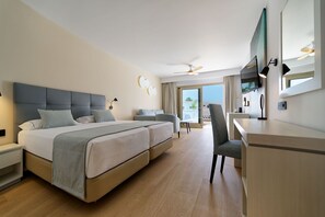 Habitación de hotel con una cama grande, un escritorio, una silla, un ventilador de techo y un ventanal amplio.