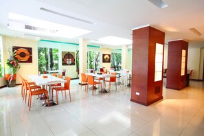 A spacious dining area with multiple tables and chairs, large windows with a view of trees, and modern interior design. - Calypzo Bangkok (Bangkok)
