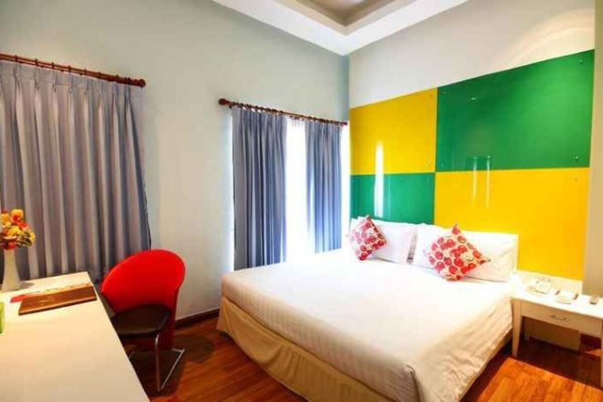A hotel room with a bed, a desk, a chair, and curtains.