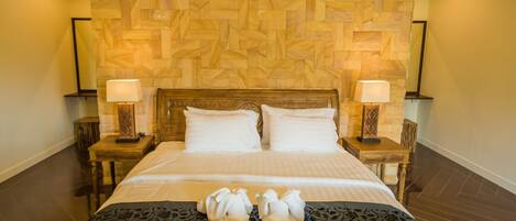 A neatly made bed with two pillows, a wooden headboard, and two bedside lamps.