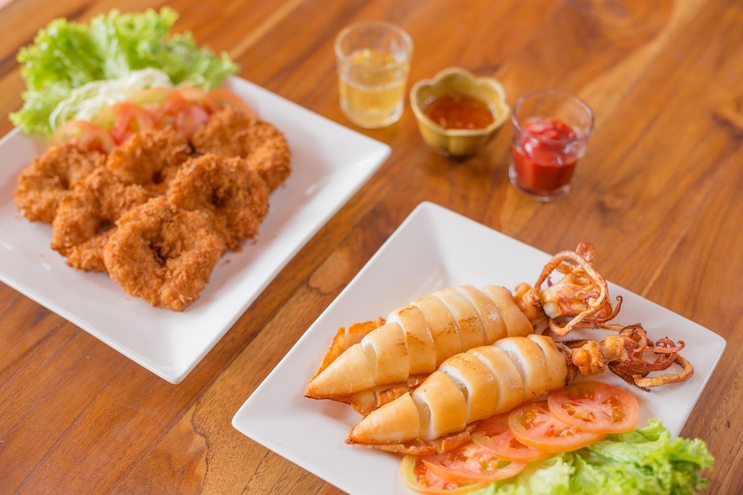 A plate of fried food with a side salad and condiments.