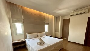 A modern hotel room with a large bed, a bedside table, a nightstand, a window, and an air conditioning unit. - Calypzo 2 (Bangkok)