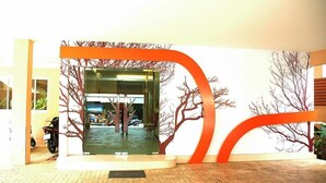A reception area with a glass door, a tiled floor, and a wall with tree designs. - Calypzo 2 (Bangkok)