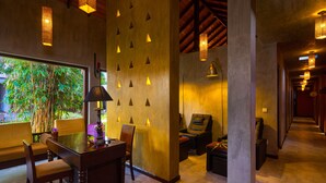 A spacious lobby with a wooden ceiling, a reception desk, seating area, and a large window with a view of greenery.