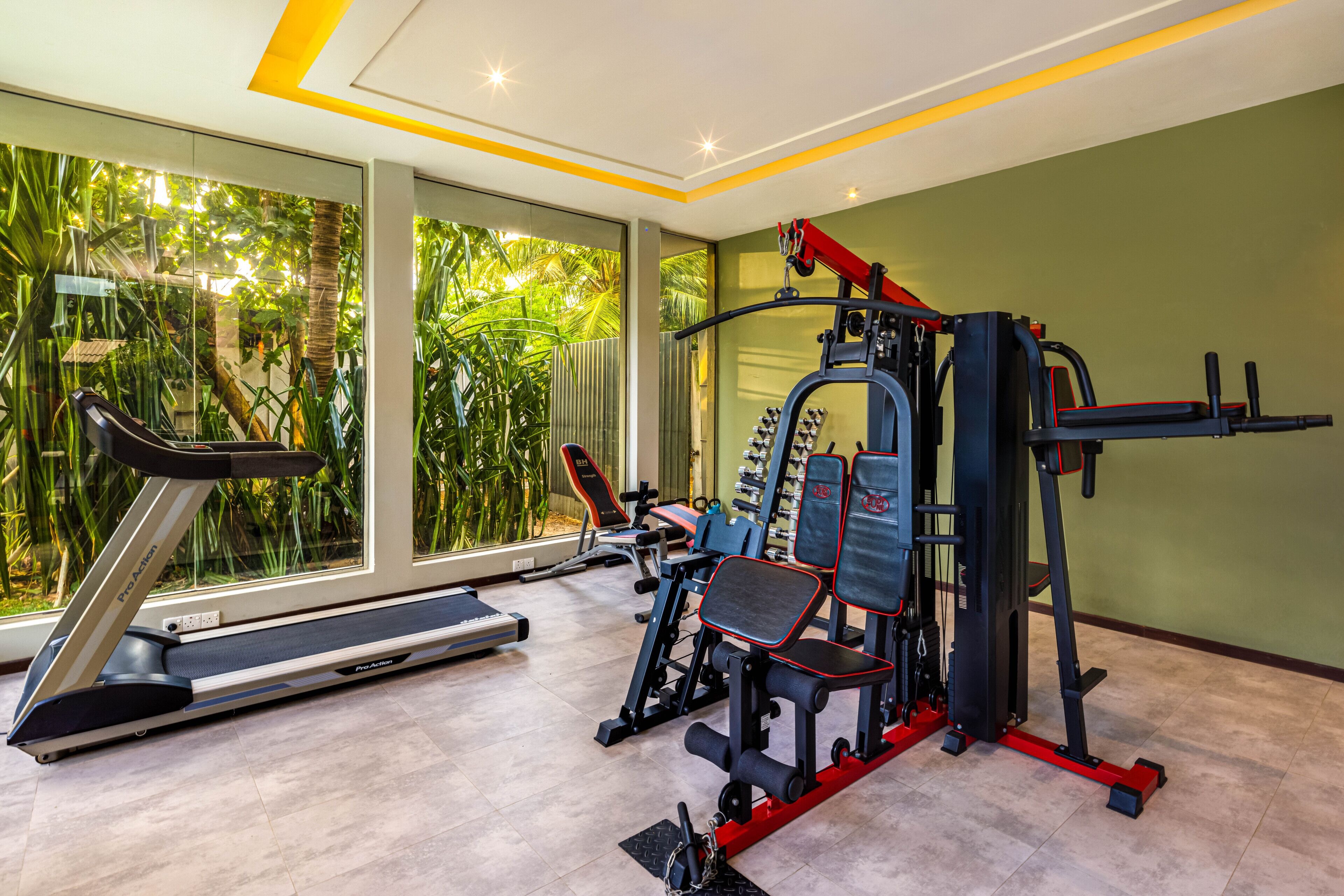 Ein Fitnessstudio mit Laufband, Kraftgeräten und einer Trainingsbank.