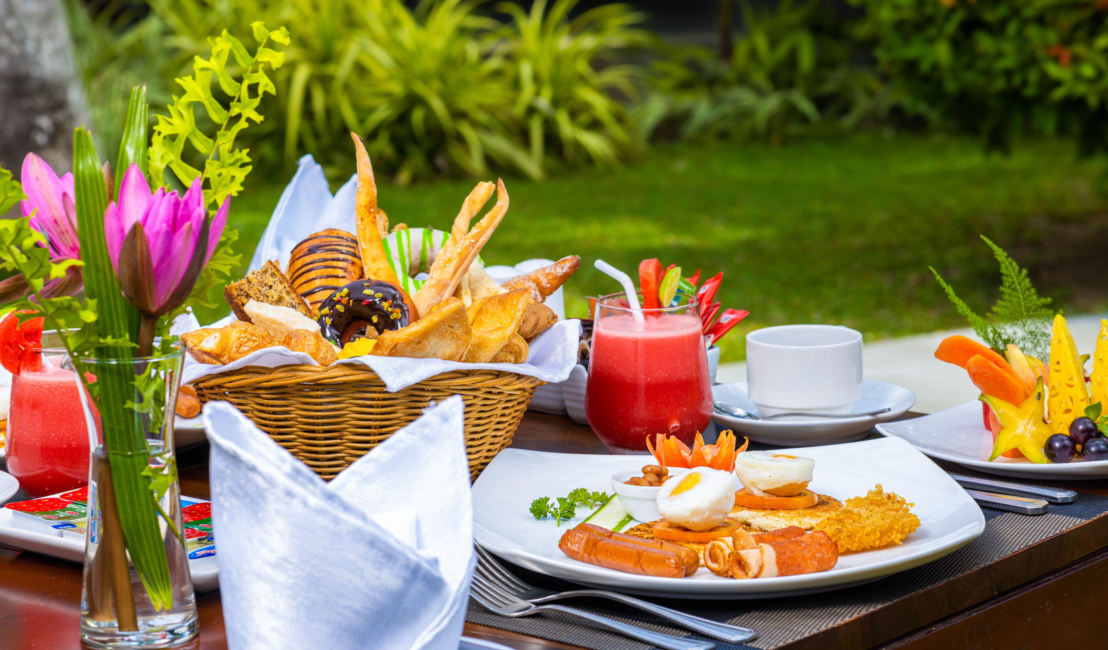 Un buffet de petit-déjeuner comprenant diverses pâtisseries, un assortiment de fruits et une boisson rouge.