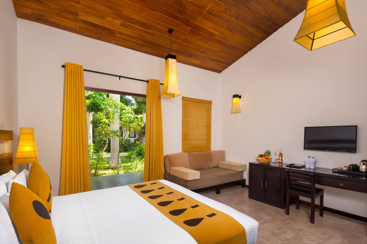 Ein Hotelzimmer mit Bett, Sofa, Schreibtisch und Fernseher.
